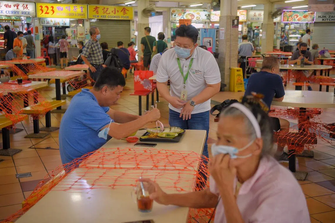环境局人员提醒食客用餐完毕后归还托盘。（海峡时报）