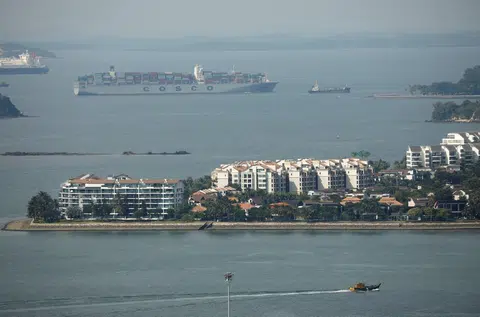 一艘集装箱货船正驶过新加坡豪华公寓圣淘沙升涛湾（Sentosa Cove）对出的海域。（路透社）