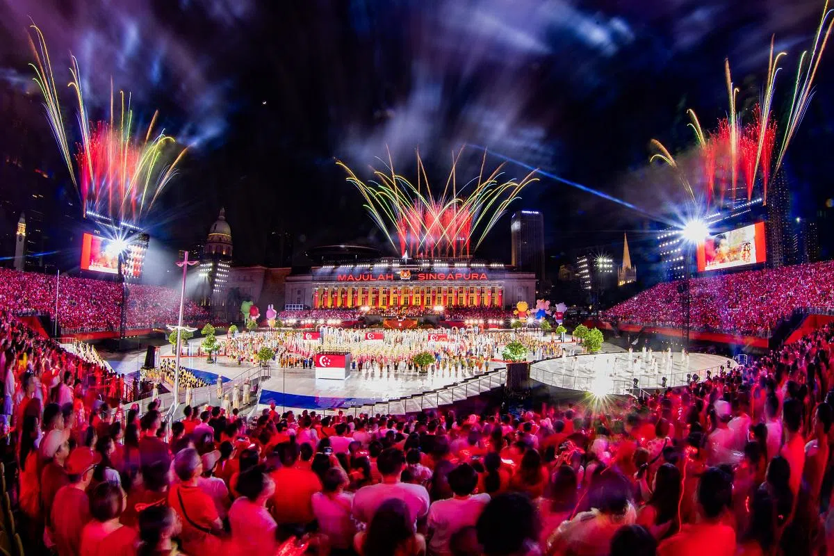 在2024年国庆庆典的尾声，众人齐唱国歌。此时，璀璨的烟花照亮夜空，将现场氛围推向最高潮。（联合早报）