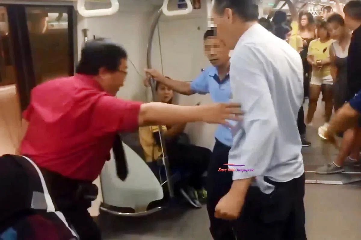  地铁到站后，穿红色制服的SMRT地铁工作人员走进车厢主持公道，最后将两名吵架的大叔请出车厢。（视频截图） 