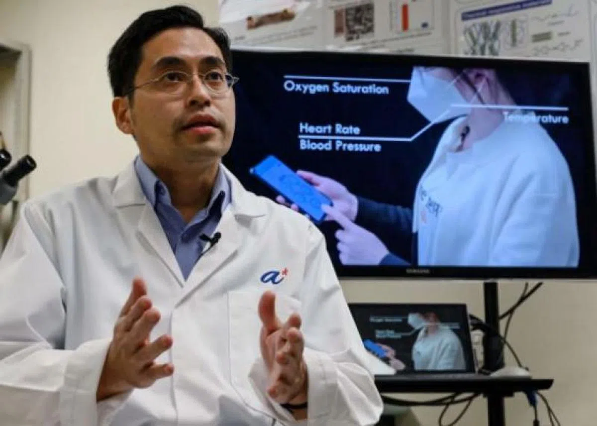  罗贤俊透露智能口罩的研究动机，右上的屏幕则展示了口罩的功能。（法新社） 