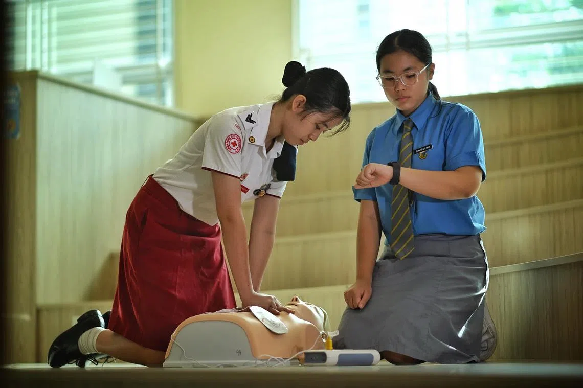 13岁的Elina（右）和16岁的Gracias（左）受访时示范如何进行心肺复苏，动作专业标准。（海峡时报）