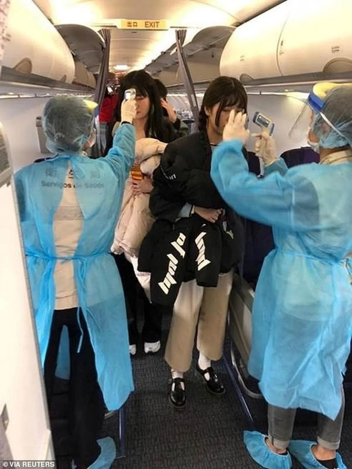  从武汉飞往澳门的航班上，医护人员全副武装为乘客测量体温。（路透社） 
