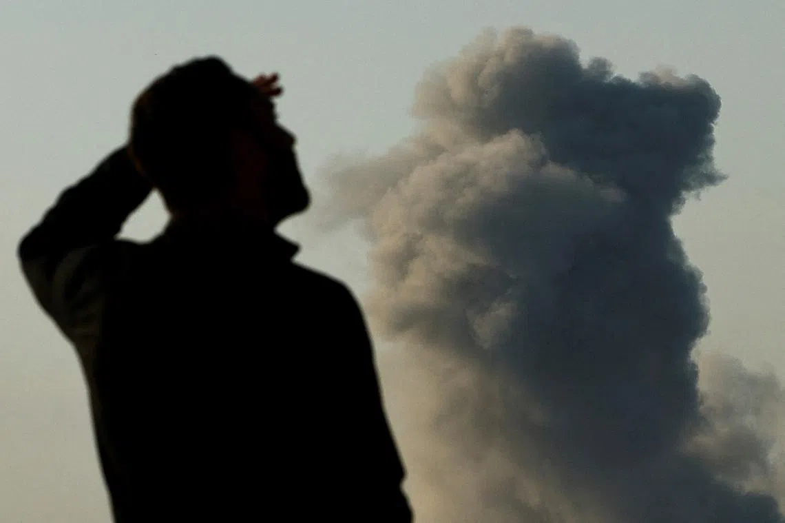 以哈冲突中，一名士兵正在检查远处的轰炸情况。（路透社）