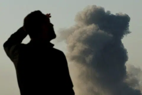 以哈冲突中，一名士兵正在检查远处的轰炸情况。（路透社）