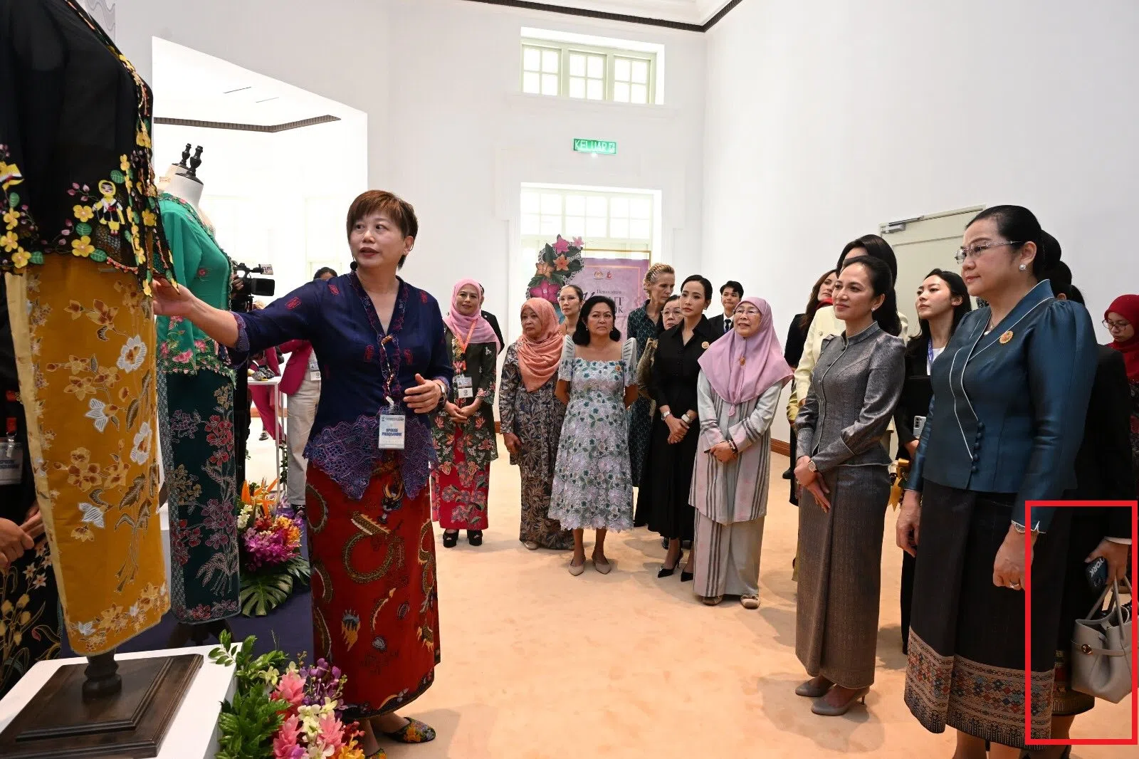 老挝总理夫人万达拉·西潘敦（右一）由身后的随行人员协助拎包。