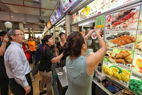 蒙巴登区议员林谋泉（左一），经常在辖区内的旧机场路熟食中心与小贩交流联系。（联合早报）