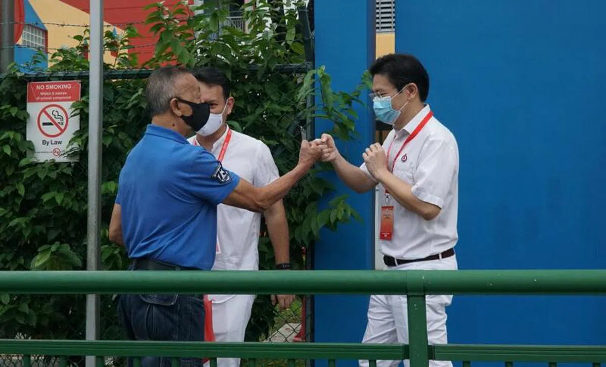  黄循财7月10日在投票站外与选民互动。（海峡时报） 