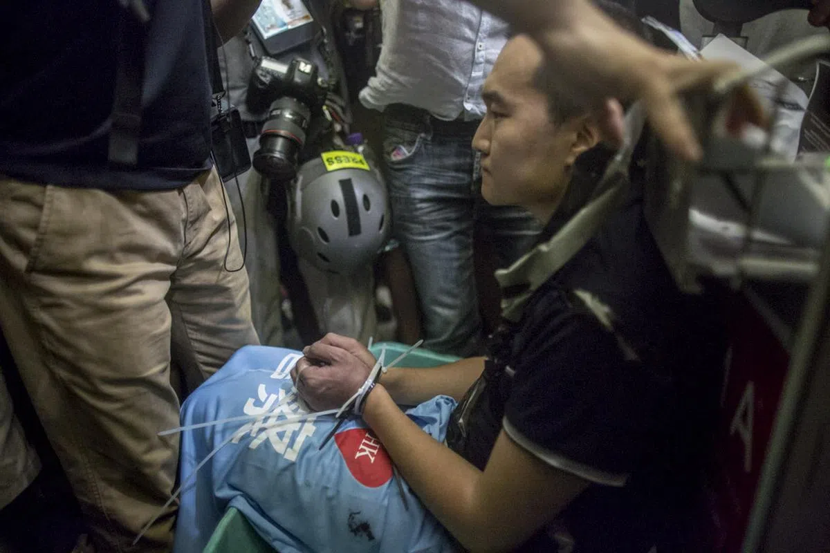  《环球时报》记者遭示威者捆绑在行李车上。（端媒体） 