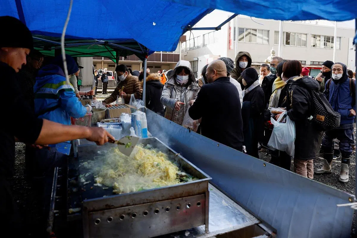 地震灾民在排队领取热食与饮料。（路透社）