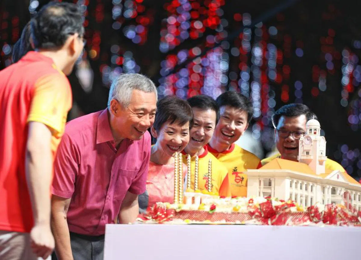  李显龙总理致辞后上台为华中校庆蛋糕吹蜡烛。（联合早报） 