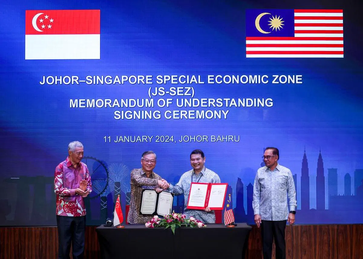 出访马国柔佛新山的李显龙总理（左一）和安华（右一）见证新加坡贸工部长颜金勇（左二）和马国经济部长拉菲兹（右二）签署有关柔新经济特区的谅解备忘录。（联合早报）