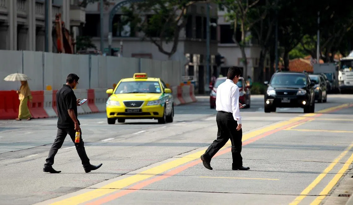 新加坡有许多低头族往往忽略身边的潜在危机，过马路时也不放下手机。（新报）