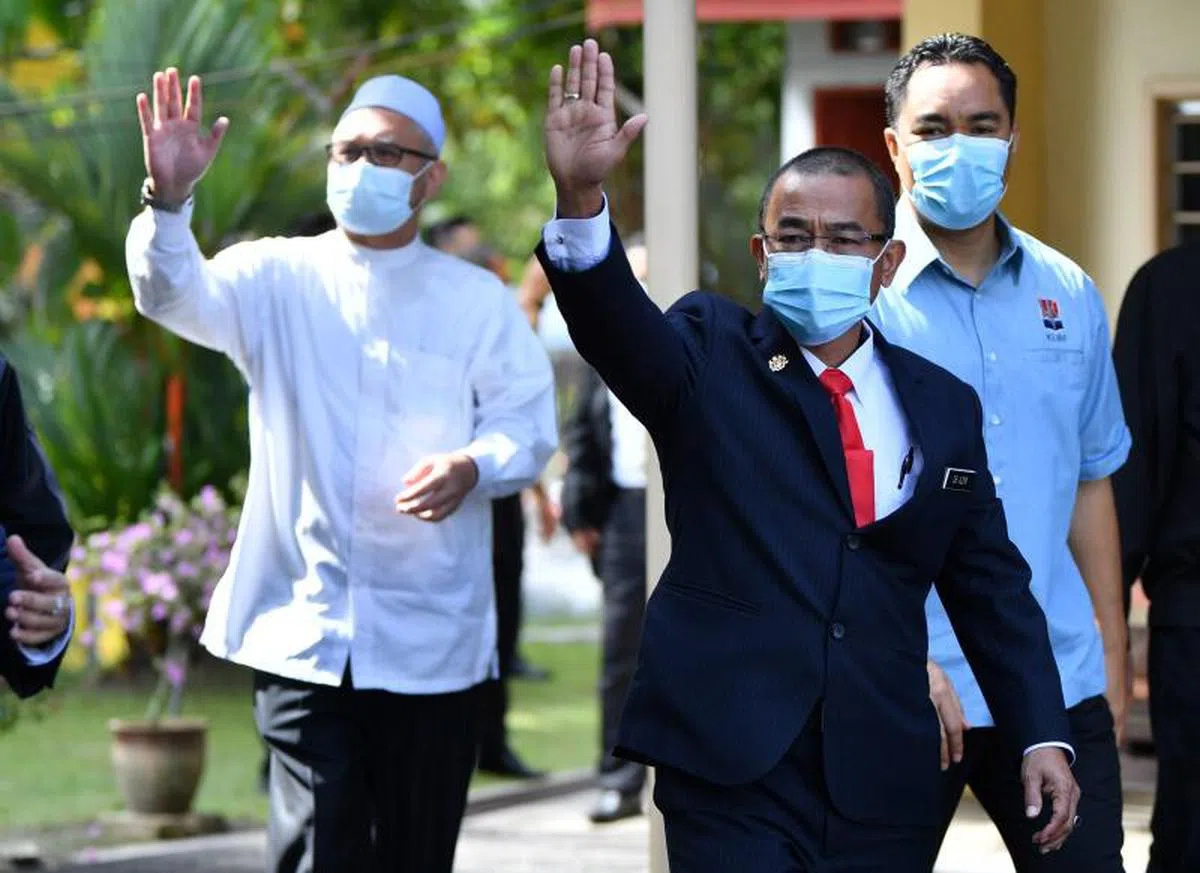  马来西亚卫生部第一副部长诺阿兹米（中）和 霹雳州行政议员拉兹曼（左一）在法庭宣判后步出庭外，面对大批媒体镜头，不约而同举起手示意。（星洲日报） 