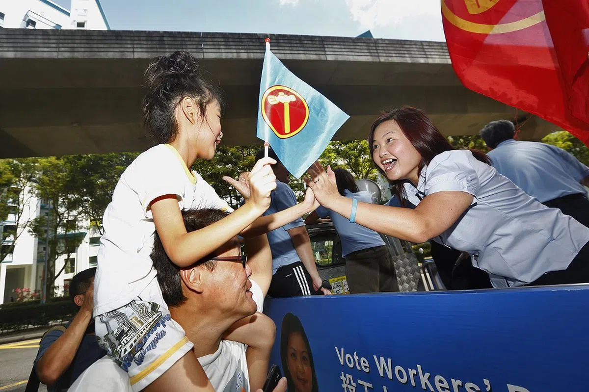 工人党候选人李丽连（右）在2013年榜鹅东补选竞选期间跟支持者击掌致意。她最终以54.50%的选票击败另外三名候选人。（海峡时报）