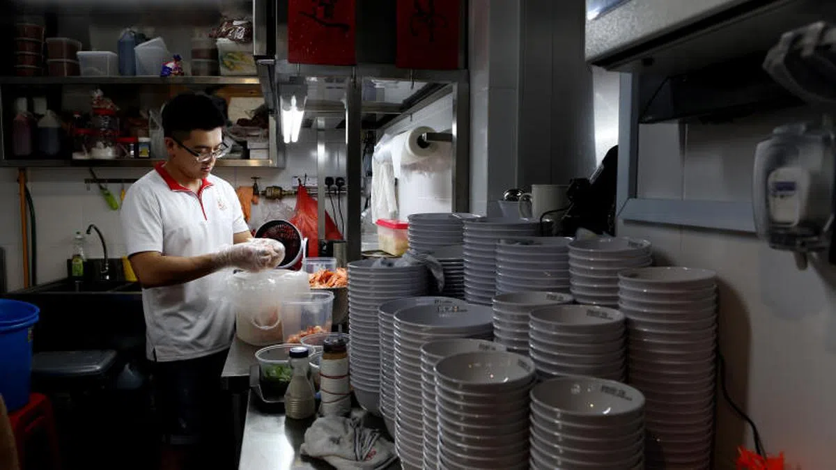  年轻小贩傅志荣在白沙中小贩中心经营“富丽虾面”档口，作为第二代小贩，他不只是传承传统口味，而是要发挥小贩文化的潜在价值。（联合早报） 