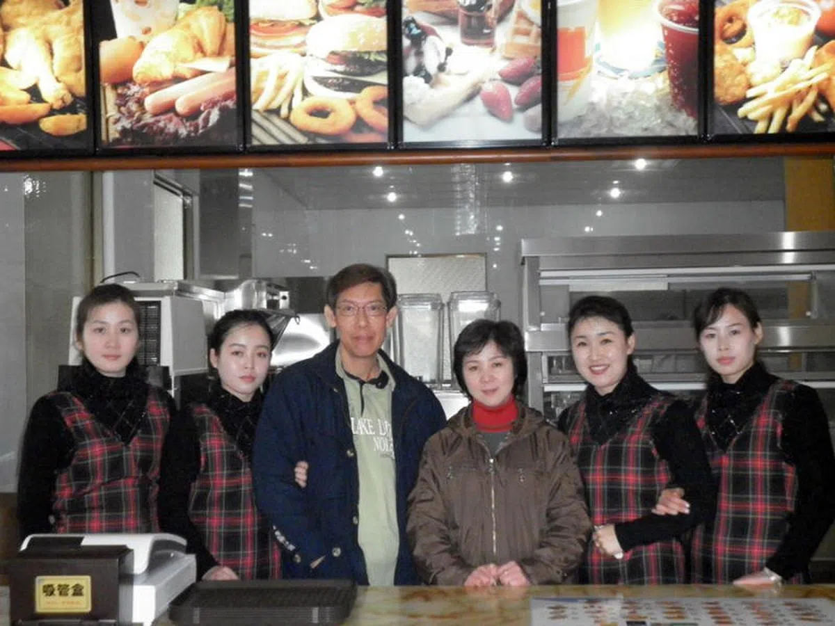  我国商人苏炳强（左三）十年前赴朝鲜平壤，与另两名新加坡籍创办人一起设立快餐店卖汉堡。（互联网） 