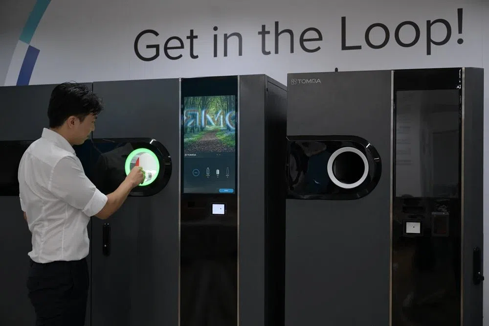 回收机供应商陶朗新加坡负责人示范如何把瓶罐投进回收机。