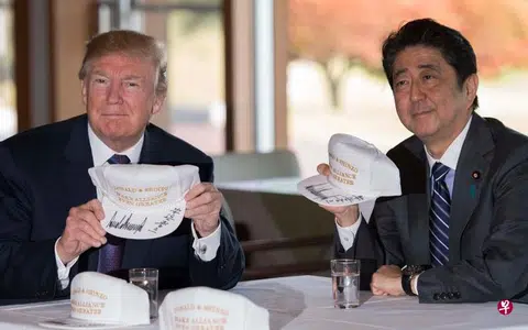 日本首相安倍晋三（右）同到访的美国总统特朗普共进午餐后，一起打高尔夫。两人还在一些印有“特朗普和安倍让美日同盟更加伟大”字样的帽子上签名留念。（法新社）