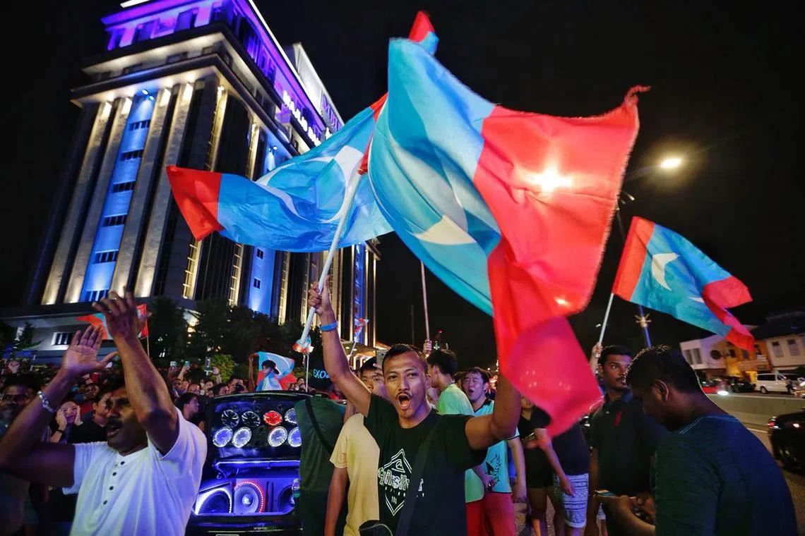 509大选隔天，希盟支持者举着旗帜走上街头庆祝希盟大胜。（海峡时报）