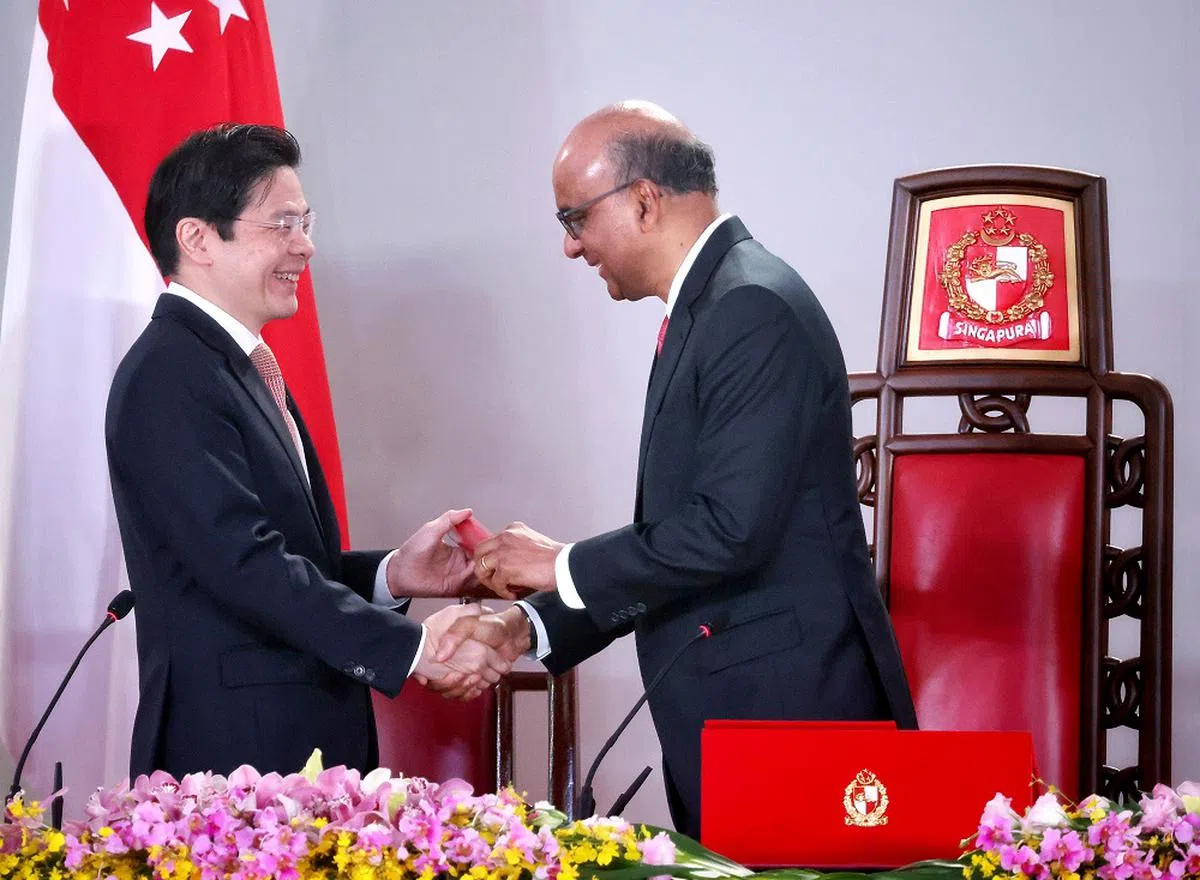 黄循财总理（左）和尚达曼总统都考获哈佛肯尼迪政府学院的公共行政硕士学位。图为黄总理在5月23日的就职仪式上，从尚达曼总统手中接过委任状。（海峡时报）