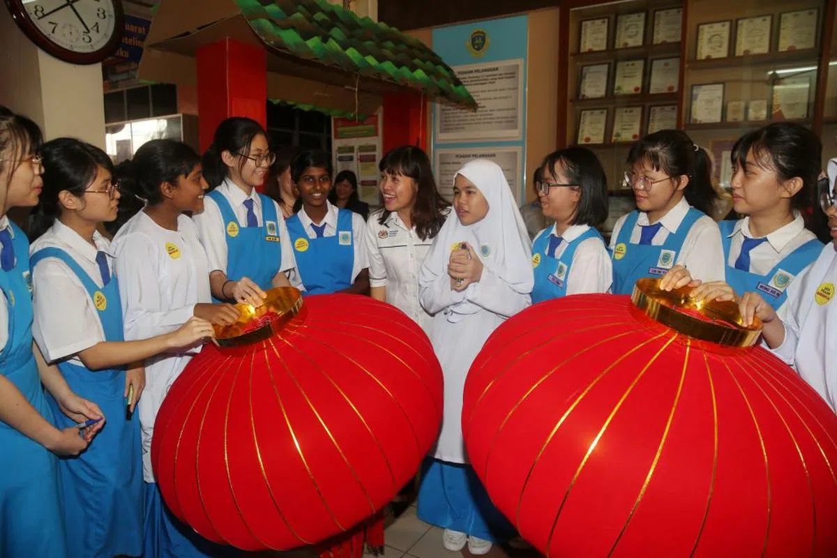  张念群（右五）与正在准备新年灯饰的学生合照。（星洲日报） 