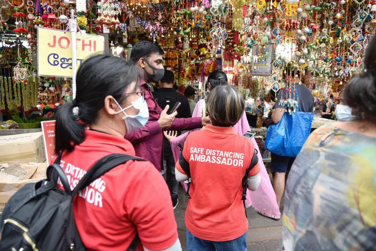  安全距离大使在各大公共场所巡逻，提醒公众遵守相关规定。（海峡时报） 