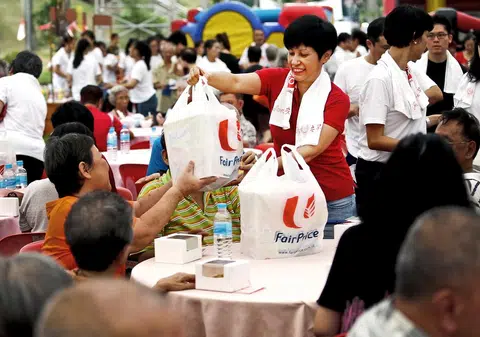 图为英兰妮在2015年东陵—经禧区的一场活动中，向建国一代居民们派发迷你发糕和礼包。（联合早报）