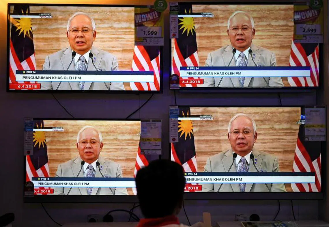 马来西亚首相纳吉在4月6日宣布解散国会，在购物商场的荧幕前，市民驻足观看电视直播。（法新社）