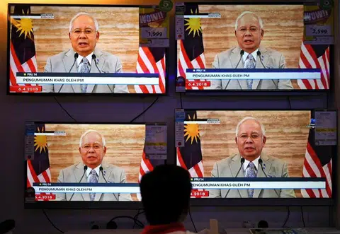 马来西亚首相纳吉在4月6日宣布解散国会，在购物商场的荧幕前，市民驻足观看电视直播。（法新社）