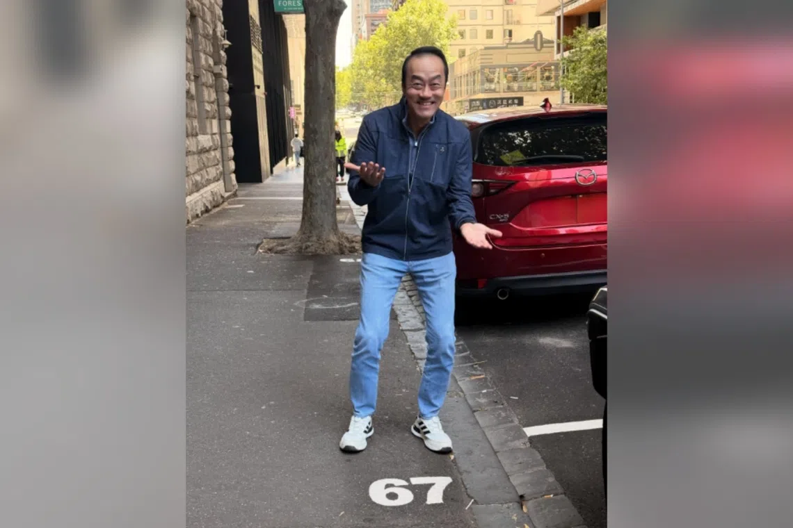 人力部兼卫生部高级政务部长许宝琨医生目前在国外旅游，站在数字“67”前，摆出一个手掌上下摆动的姿势。