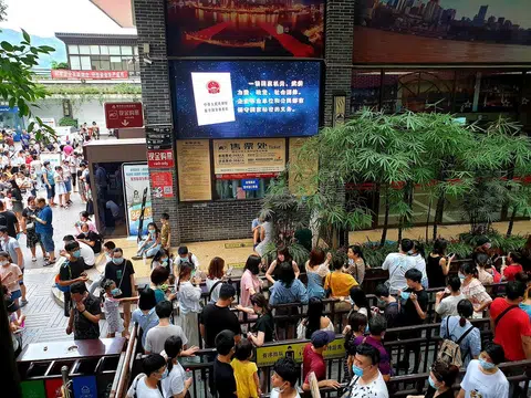 中国7月中恢复境内跨省区市团队旅游，饱受冠病疫情冲击的重庆旅游业加速跟进，著名地标解放碑在8月盛夏高温下明显可见游人回流。渝中区一端的长江索道，上百游客大排长龙购票搭乘索道过江。（联合早报）