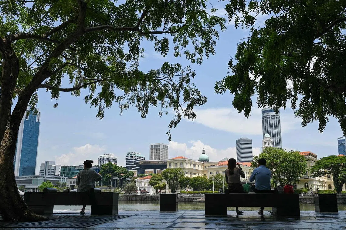 新加坡人在新加坡河畔吃午餐，对岸是新加坡国会大厦和高等法院。（海峡时报）