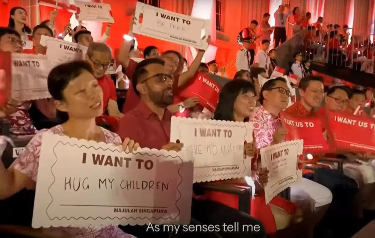 阿裕尼集选区议员严燕松兴奋举起写着“我要自由”的“心愿牌”，仿佛在呼应坐在前排、写上“我要无怨无悔”的反对党领袖毕丹星。（视频截图）