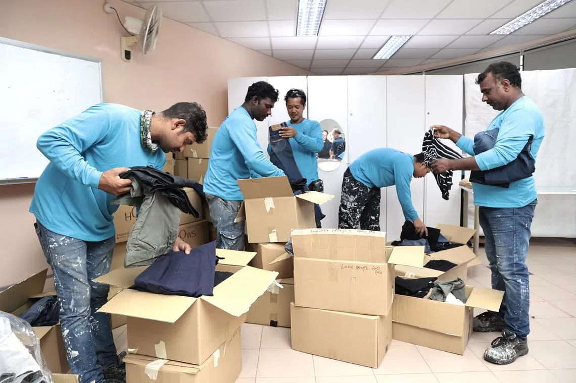 油漆承包公司WB私人有限公司的客工12月12日在武吉班让民众俱乐部，挑选居民捐赠的长裤等衣物。（联合早报）