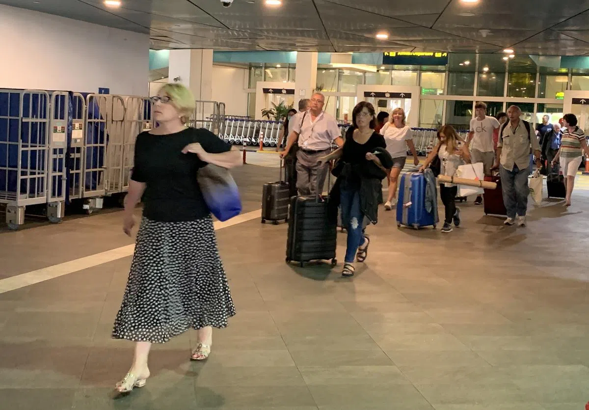  上午8点55分：第一批下船的乘客抵达新加坡关卡。这批20人左右都是外国人和中年人为主。他们过了关卡后便立即被护送至标有“Orange K SQ978”的旅游巴士上，直奔樟宜机场。（新明日报） 