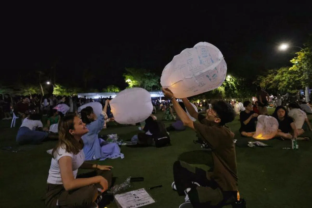 比较乐观的出席者，仍然写下祝福，开了LED灯，手动让天灯“飞”起来。（海峡时报）