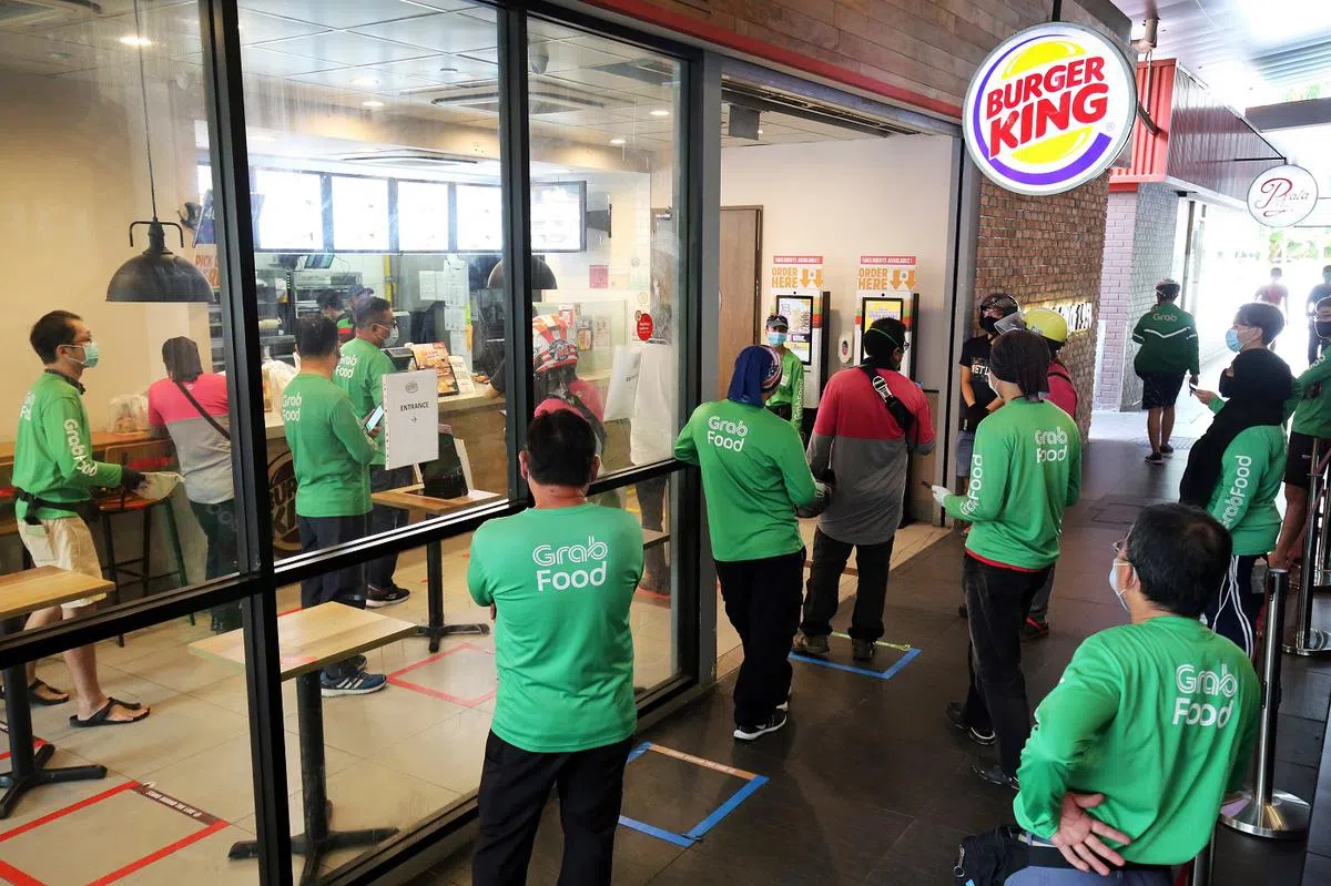 冠病疫情期间，民众开始转向网上订餐和送餐服务。尤其是尖峰时段，快餐店外常有送餐员排队取餐，等候时间可长达一小时。（联合早报）