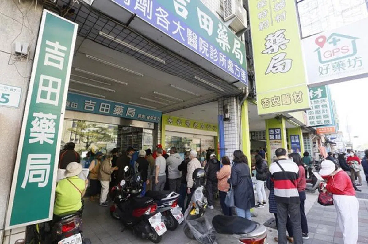  台湾口罩实名制实施后，位于高医对面的一家健保药局出现排队人龙，但现场秩序良好。(中央社) 