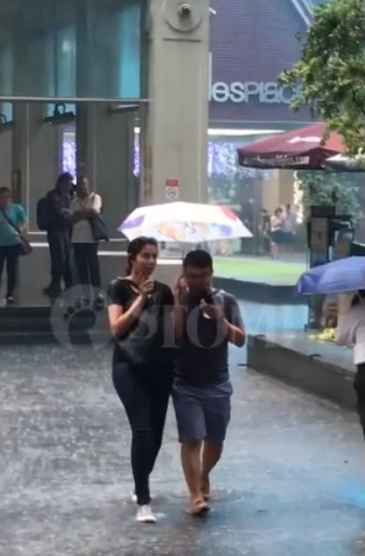  女大学生用自己的雨伞接送被困于雨中的陌生人。（Stomp视频截图） 