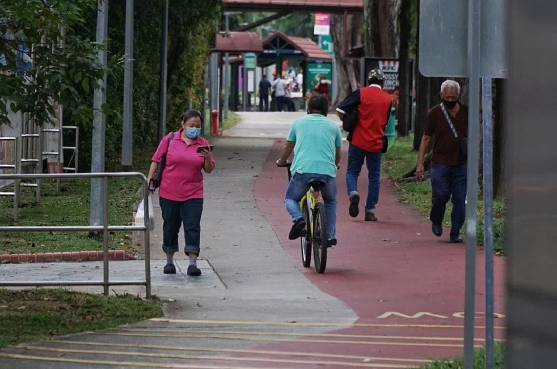 明明区分了人行道和脚踏车骑道，不过行人没在管。其中一人还一边走路，一边看手机。（海峡时报）