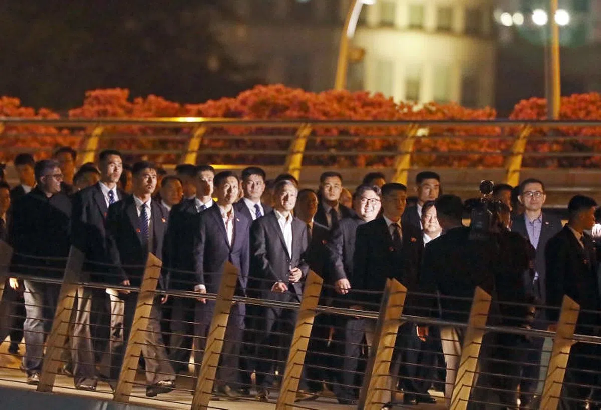  6月11日晚，金正恩（中间戴眼镜者）在维文和王乙康的陪同下，步上金禧桥观赏鱼尾狮。（联合早报） 