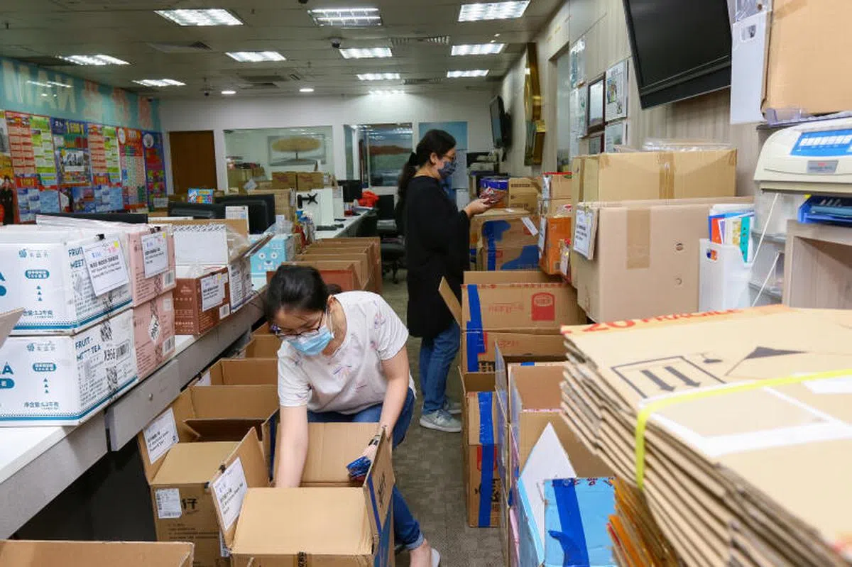  2021年5月16日起至6月13日进入“高警戒解封第二阶段”，受影响业者更得发挥创新精神，调整营运模式，让生意得以继续。位在牛车水珍珠坊的南和旅行社门面都用旅游海报遮了起来，变成了打包外国美食的空间。南和旅行社资深操作员吴玮伦（前）与业务负责黄媚凤也变身包装人员。（新明日报） 