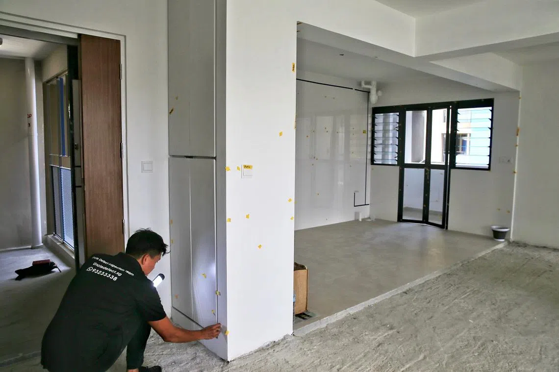 缺陷质检员在为刚交付的预购祖屋进行检查，贴上黄色贴纸的都是所找到的瑕疵或缺陷。（海峡时报）