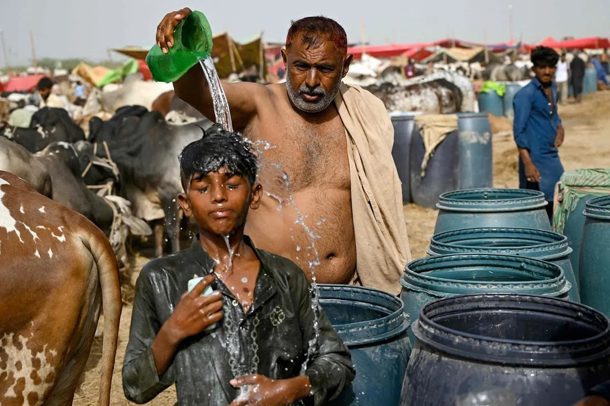 巴基斯坦冲水洗澡降温的小男生。（路透社）