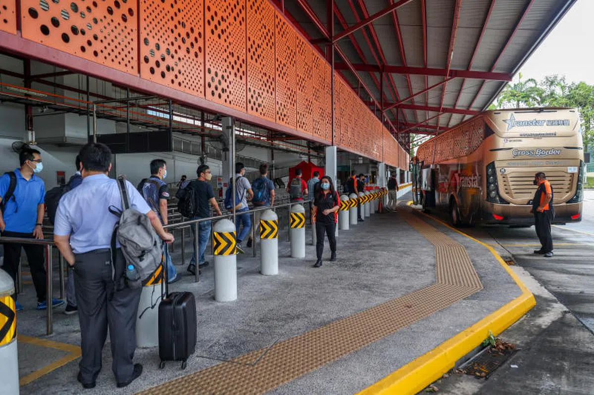 兀兰临时转换站的现场工作人员拎着大包小包，演练乘客上下车。（联合早报）