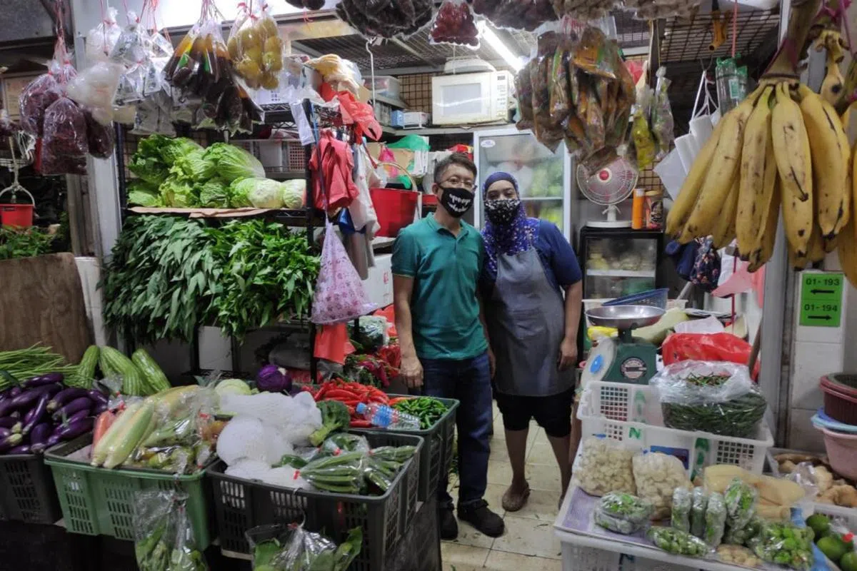  拉希达（右）与丈夫在芽笼士乃巴刹一同经营蔬果摊。（海峡时报） 