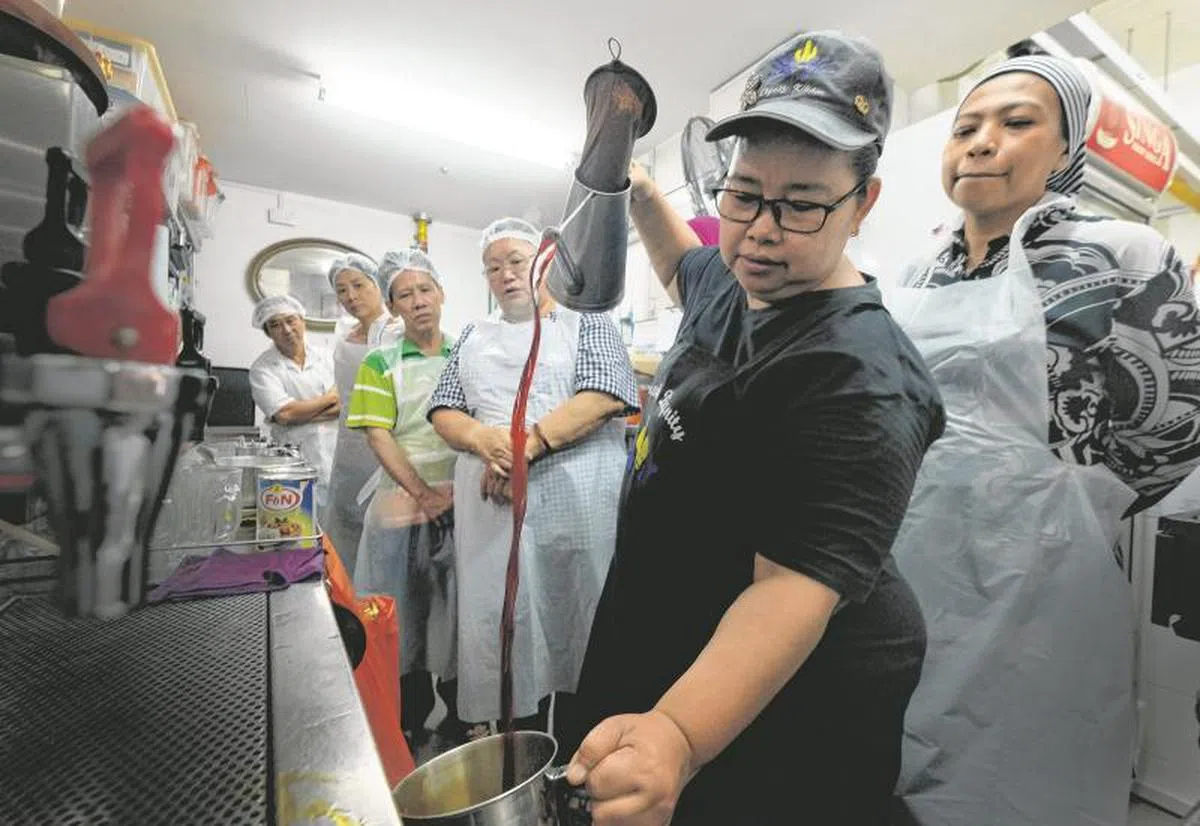  厨尊拉茶导师Liza向学员示范拉茶的几个关键技巧，例如拉扯距离应该多远，握着铁杯的那只手千万不要触碰杯子底部以免被烫伤。（海峡时报） 