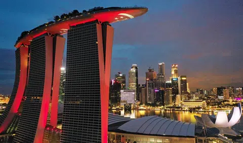 远处的城市夜景依然璀璨， 与滨海湾金沙酒店客房的寥寥数盏灯形成强烈对比。（联合早报）