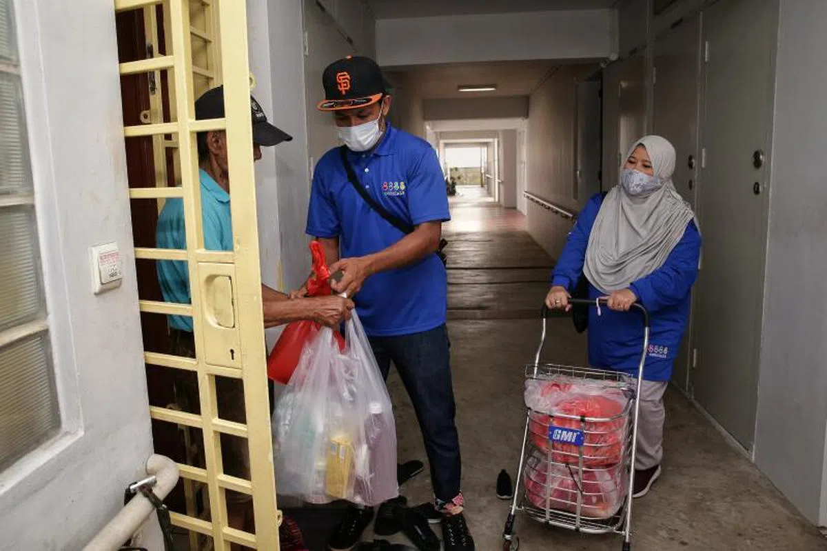  萨里玛（右）与义工向义顺居民派发生活必需品。（每日新闻） 